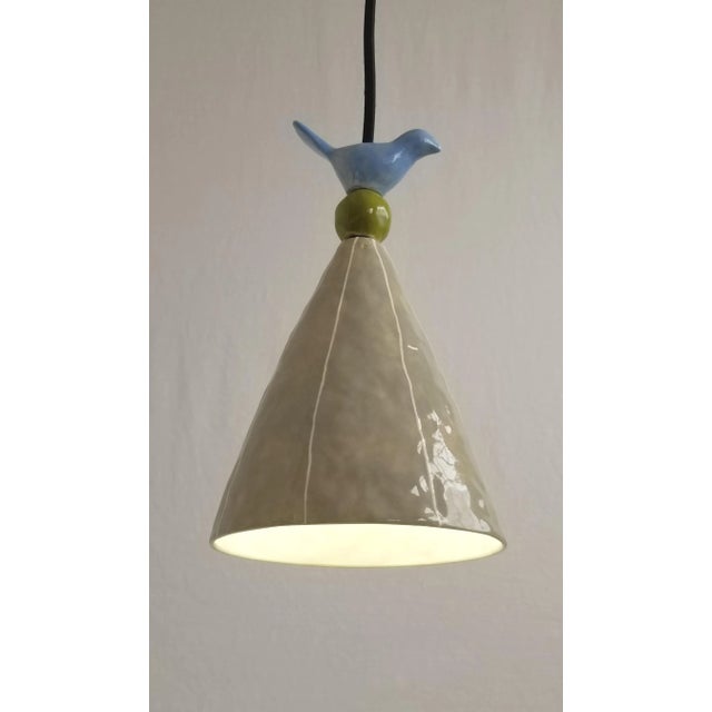 Gray ceramic cone shaped pendant light is handmade with blue and green accent beads and detailed with thin, white stripes....