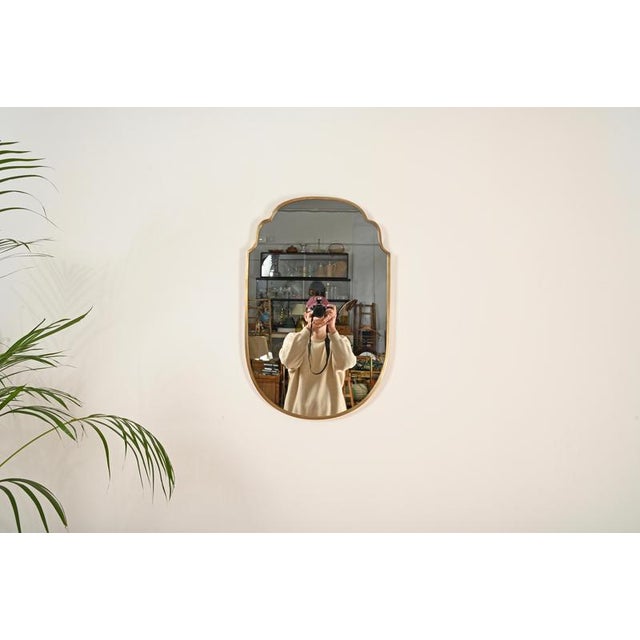 Marvelous large shield-shaped mirror with a solid brass frame. This refined and distinctive piece was produced in Italy...