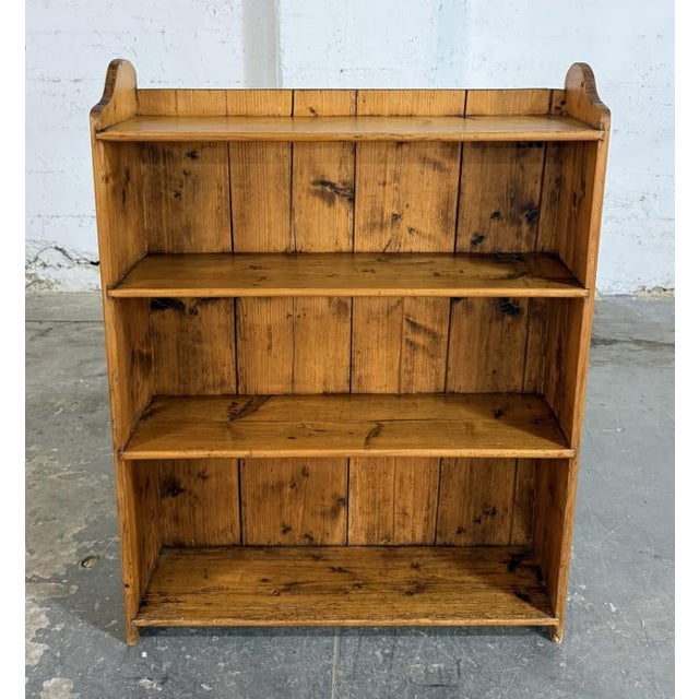 This antique pine bookcase features simple open shelving, a plank-style back, and a warm honey-toned finish that...