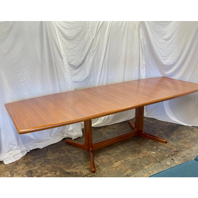 Gorgeous boat-shape Danish teak extendable dining table with (2) 24” wide leaves, solid double pedestal base and bull nose...