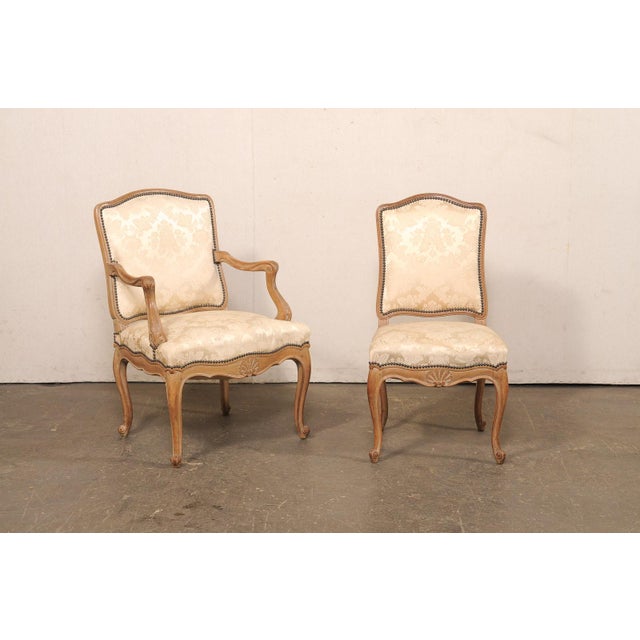 A set of ten carved and upholstered French dining chairs from the mid-20th century. This mid-century set of chairs from...