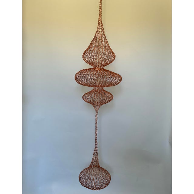 A striking handwoven wire sculpture executed in the spirit of Ruth Asawa, featuring an elongated cascading form composed...