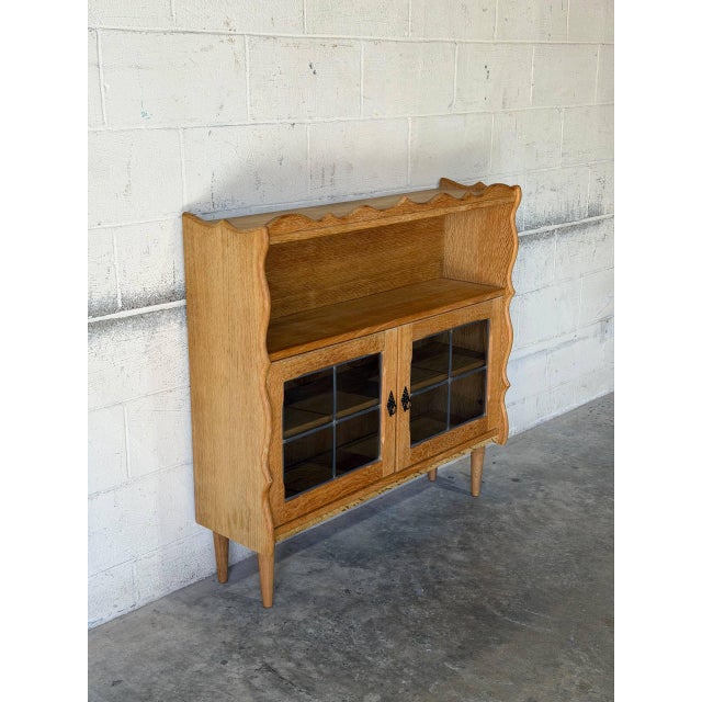 This distinctive bookcase features an open upper shelf beneath a beautifully scalloped top edge. The lower section offers...