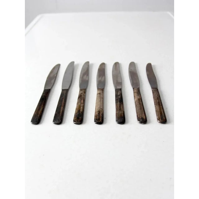 This charming collection includes six vintage dinner knives and one matching butter knife. The knives feature beautifully...