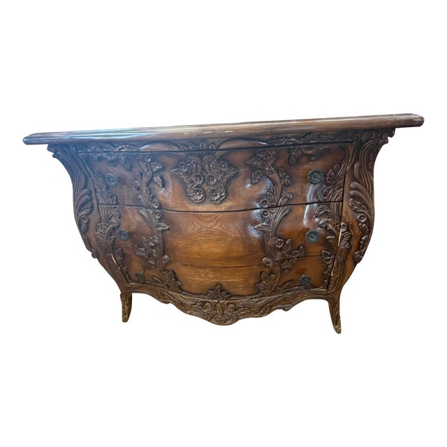 This antique bombe chest features an exquisitely carved curved front with deep floral and foliate relief, showcasing...