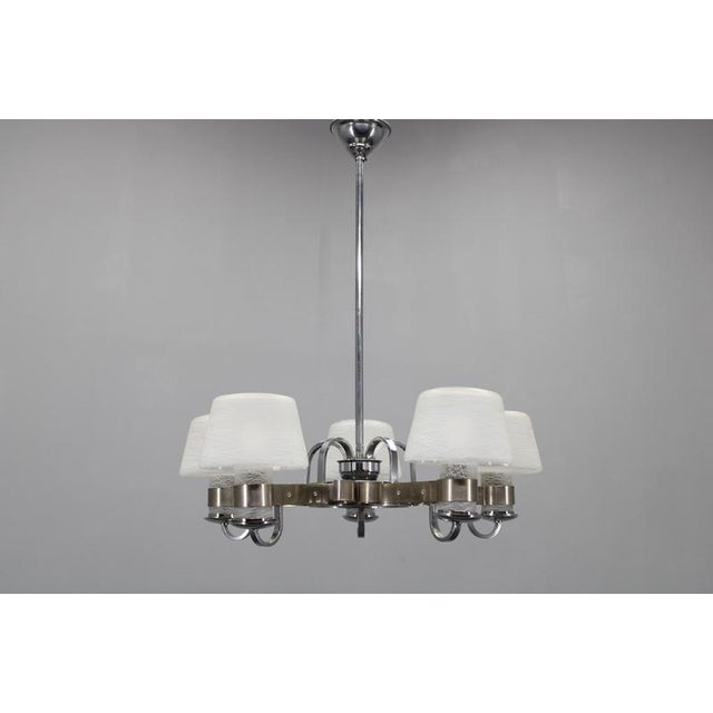 This elegant art deco chandelier originates from czechoslovakia in the 1930s and showcases a finely proportioned nickel-...
