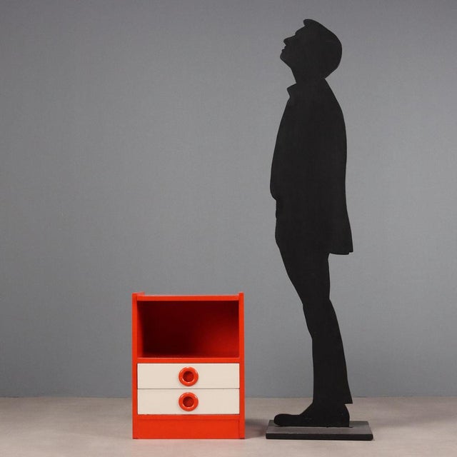 Vintage bedside table in white and orange enameled wood with open compartment and two drawers. This piece is attributed to...