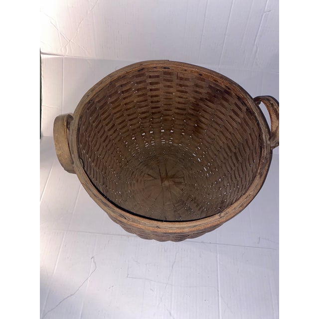 This is an antique round splint basket featuring a rich dark patina and dual integrated side handles . his is an antique...