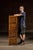 Tall oak filing cabinet featuring four drawers with inset panel faces, iron pulls, and label slots. Each drawer is built...