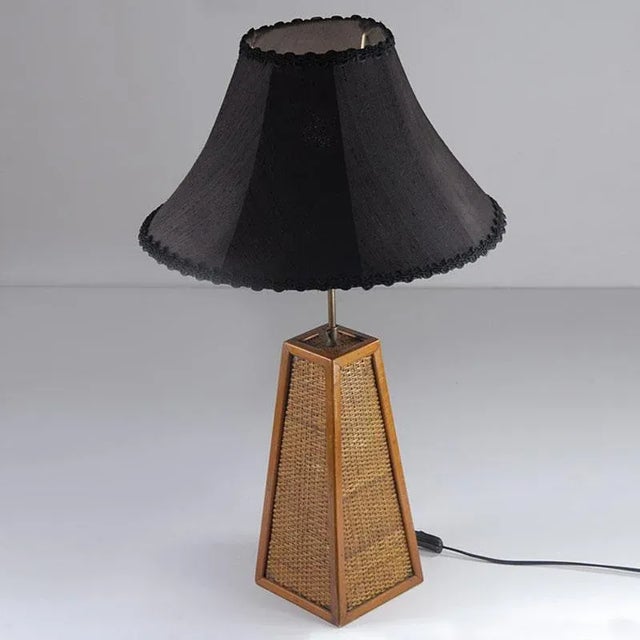 A decorative table lamp with a base made of a rattan braid. The lamp has the height of the lampshade setting. It comes...