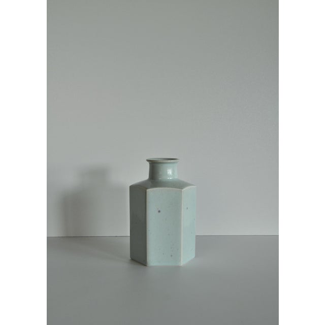 The vase has a very distinctive hexagonal body with chamfered corners and a short, collared bottle neck — a clean,...