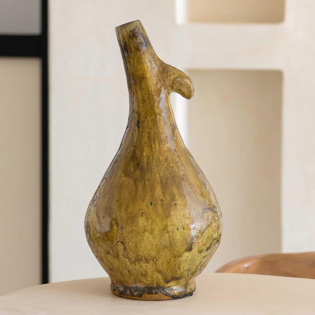 with a slender neck and bulbous base, this Tamegroute vase is finished in a translucent amber glaze. Its traditional...