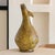 with a slender neck and bulbous base, this Tamegroute vase is finished in a translucent amber glaze. Its traditional...