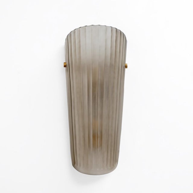 An elegant pair of italian wall lamps with handcrafted murano glass lampshades in a delicate smoky satin hue. The...
