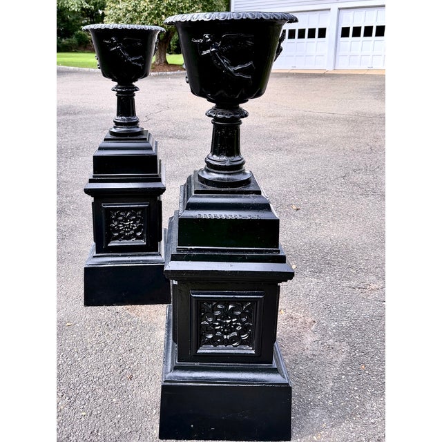 A striking pair of large and weighty antique Victorian cast iron garden urns on tall architectural pedestals, manufactured...