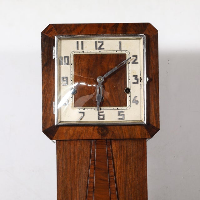 A distinguished Art Deco book matched walnut floor clock featuring deco numeral dials and skyscraper-style hands, set atop...