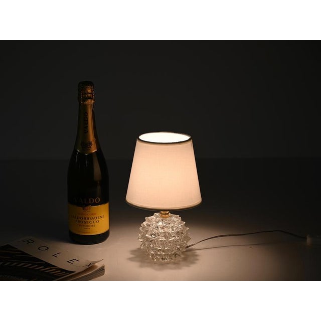Wonderful table lamp in "rostrato" mouth-blown murano glass and brass, completed with an off-white lampshade. This...