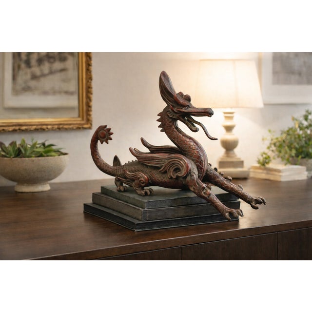 A substantial modern Chinese dragon sculpture in a dynamic reclining pose, cast in metal with a layered red bronze-toned...