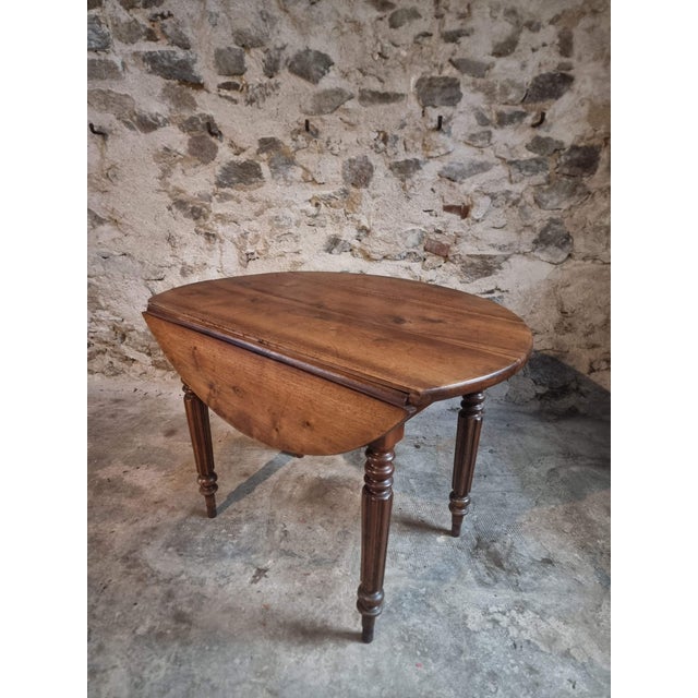 Antique French drop-leaf table in walnut, dating from the late 19th century. The table features an oval top made from...