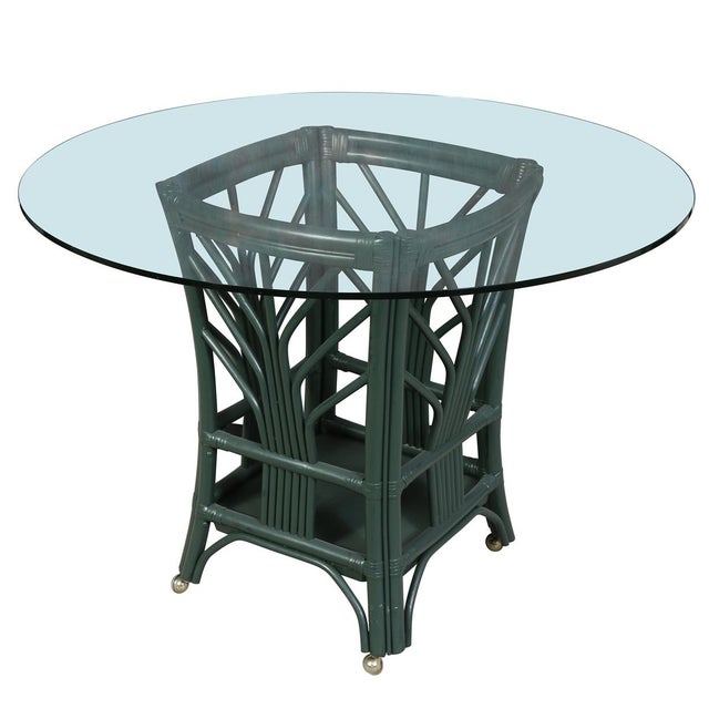 A forest green Bielecky style rattan dining set comprising a round glass top dining table and five barrel back armchairs....
