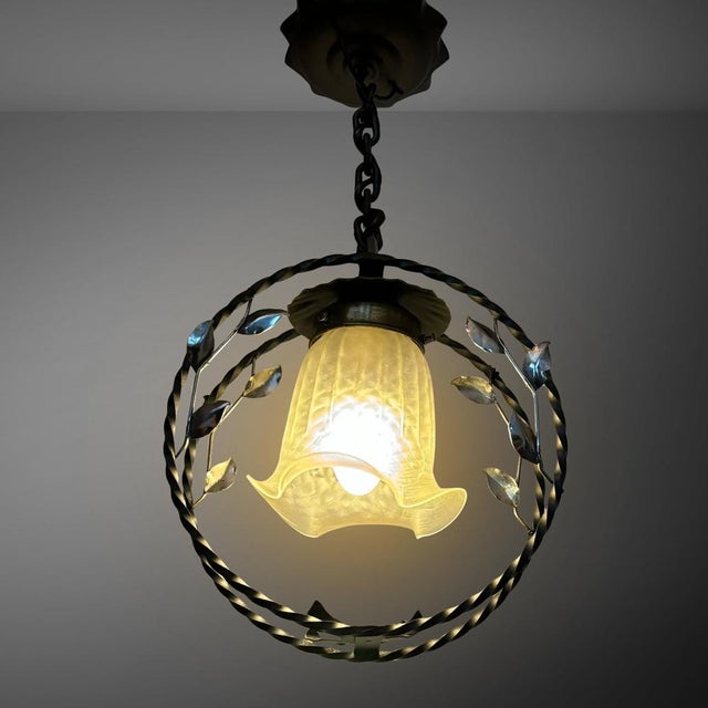 A Swedish Modern pendant lamp crafted from wrought iron, featuring a circular frame suspended by a metal chain from a...