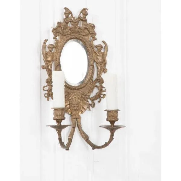 Pair of French 19th century Louis XV-style brass and mirror sconces. The hand beveled oval mirrors are surrounded by...