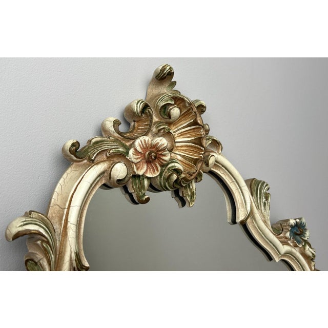 A charming vintage shabby chic wall mirror featuring an ornate decorative frame with beautifully shaped curves and floral...