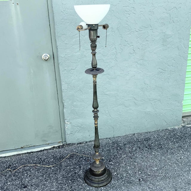 Elegant antique floor lamp featuring a tall, slender weighted metal body with ornate Neoclassical detailing throughout....