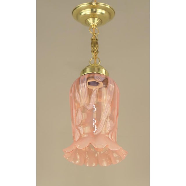 Rose-coloured Art Nouveau shade with floral pattern, 1910s The surface of the brass holder is polished. The lamp gives a...