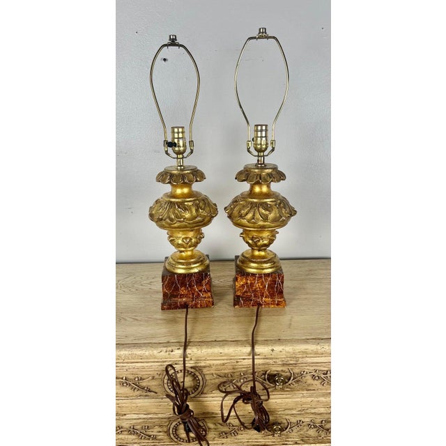 Pair of Carved Giltwood Italian Neoclassical style lamps on faux marble bases. The lamps are wired and in working...