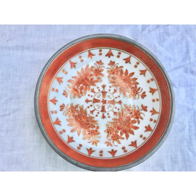 Beautiful vintage Japanese porcelain bowl features a hand-painted red and gold floral motif and is encased in decorative...