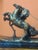 Antique bronze figure depicting a Roman quadriga, showing a charioteer or gladiator driving a two-horse chariot at full...