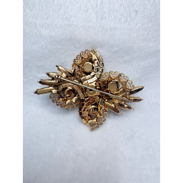 A signed Hobé © mid‑century brooch featuring layered gilt filigree and hand‑set pastel rhinestones. The sculptural floral...