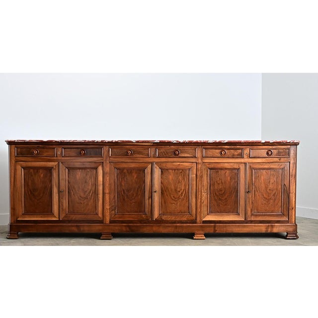 An immense 19th century French Louis Philippe walnut enfilade, the staggering scale feels even more expansive by the red...