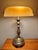 Brass and bronze-toned banker's desk lamp with an amber glass shade. Switch and outlet conveniently on base. Gives off a...