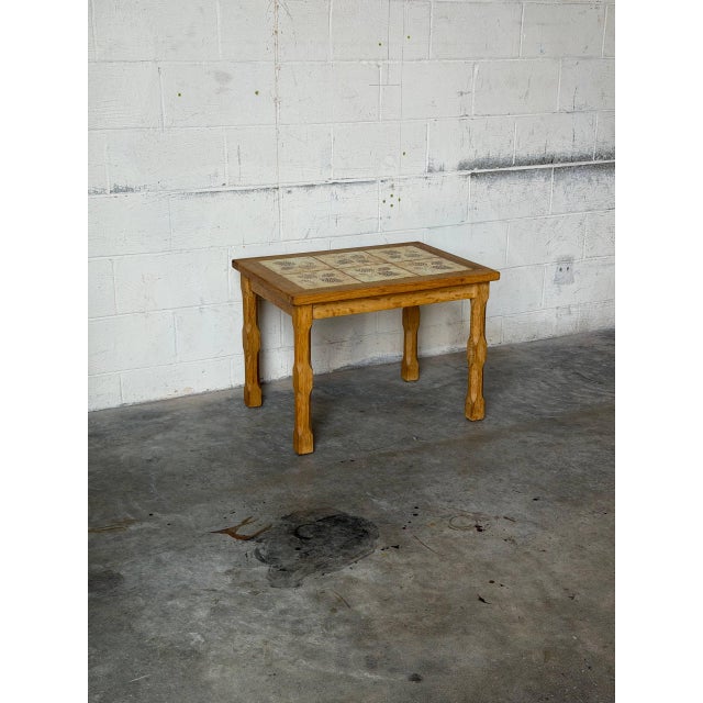 This charming coffee table features an inset tile top adorned with a detailed leaf print, complemented by classic turned...