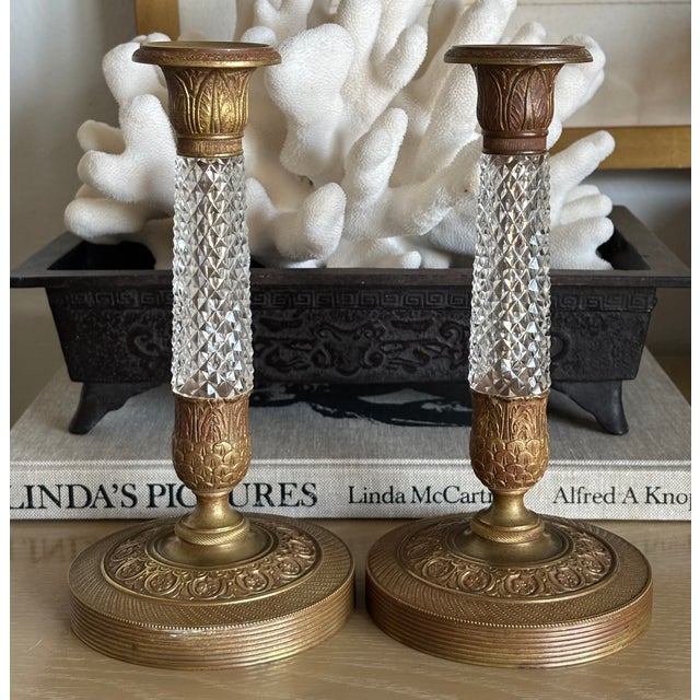 Elegant pair of antique French Empire Revival candlesticks crafted in gilt brass with faceted cut glass columns. These...