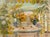 A large still life painting by Germano Russo (b.1935) featuring a round table set with colorful yellow and red and white...
