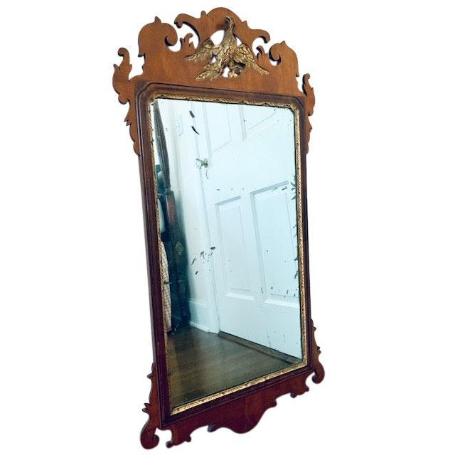 An 18th Century Federal style carved mahogany wall mirror with a parcel-gilt carved flying phoenix and original mirror...