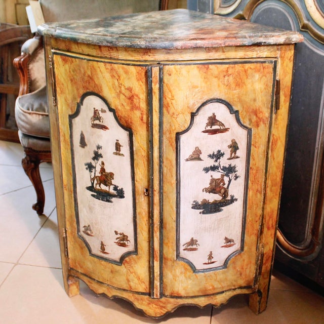 A charming brightly painted rustic bow front corner cabinet, likely Italian, painted with ochre faux marble with a deep...