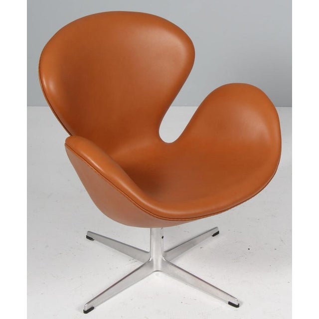 The swan chair, new upholstered in cognac aniline leather. with tilt function Made by Fritz Hansen. New upholstered. This...