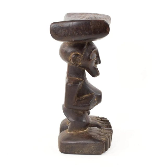 This Songye female headrest showcases a traditional cylindrical design, featuring a protruding belly button and...