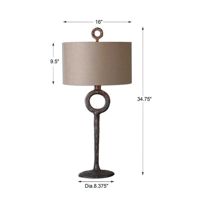 Brutalist transitional cast iron base finished in an aged rust bronze. The round hardback drum shade is a beige linen...