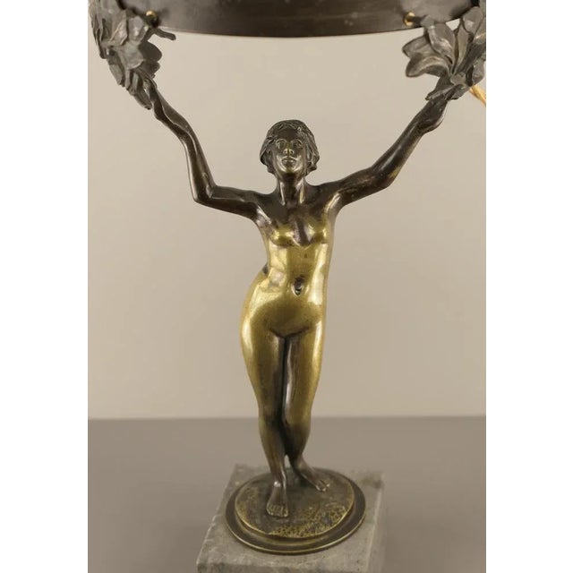 The candlestick base, mounted on a marble pedestal, is a fully sculpted representation of Daphne as a female, naked beauty...