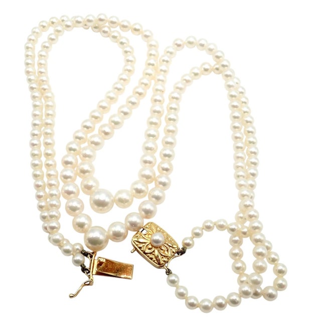 Vintage Mikimoto double strand necklace featuring luminous, graduated Akoya pearls and a beautifully engraved 18k yellow...