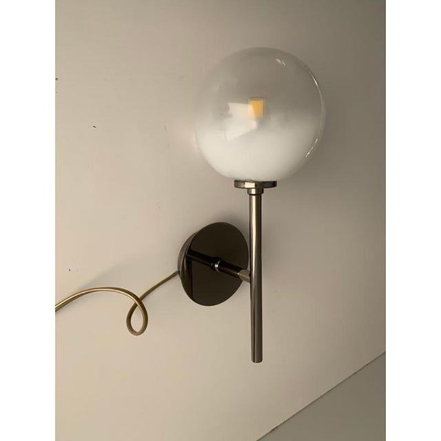 Contemporary luxury sconces in black nikel bass finishing. sphere is in transparent gradient white borosilicate glass, it...