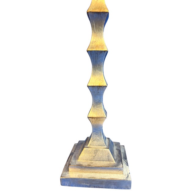 Striking sculptural table lamp featuring a geometric, modern metal base with stacked faceted detailing and a stepped...