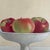 A still life painting by Elise Manville. The hyper realistic painting depicts a bowl of apples. The painting was made in...