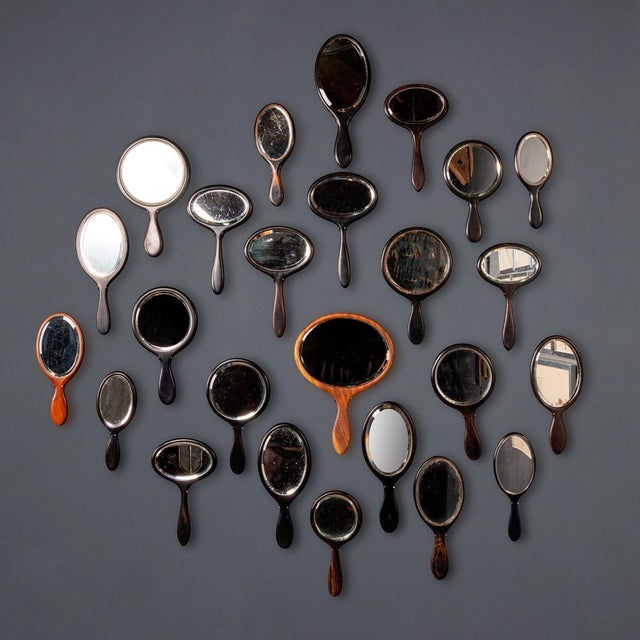 Antique 19th & 20th Century striking collection of twenty five wooden hand mirrors with bevelled glass, spanning from the...