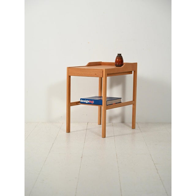 Scandinavian 1960s oak bedside table with a raised edge top and a slatted magazine rack. Vintage Scandinavian 1960s oak...